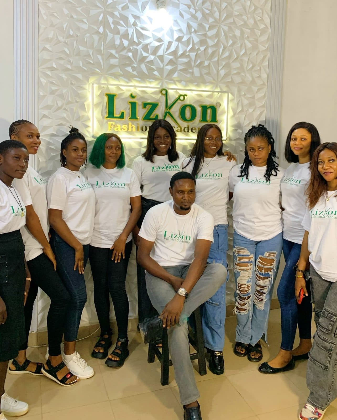 Students in Lizkon Fashion Academy T-shirts in front of the academy sign